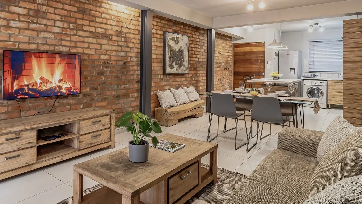 Open-plan living area with an exposed brick wall, wall-mounted television and wooden coffee table